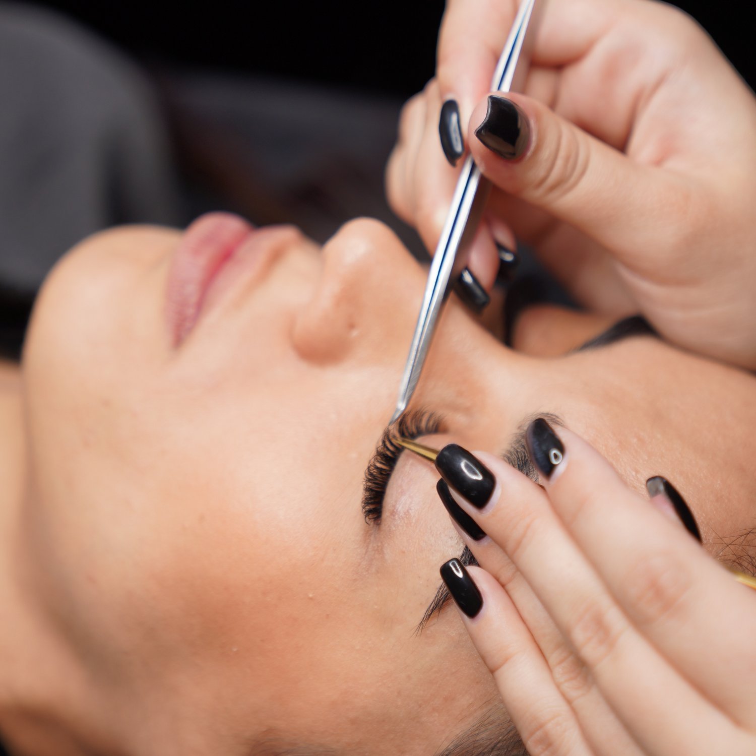 lash tech with tweezers isolating a lash extension